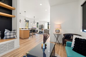 Ein modernes Wohnzimmer mit einer Couch, einem Couchtisch und einem Essbereich im Hintergrund.