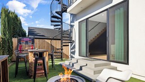 Eine moderne Außenpatio mit Feuerstelle, Wendeltreppe und Essbereich.