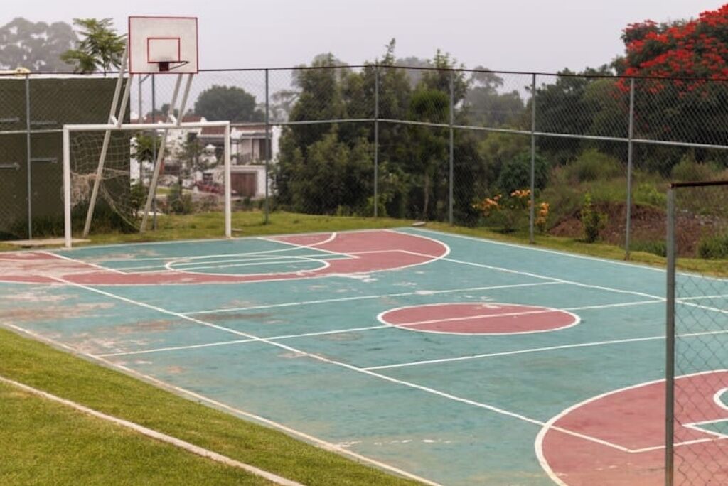 Una cancha de baloncesto al aire libre con una cerca de malla y aro.