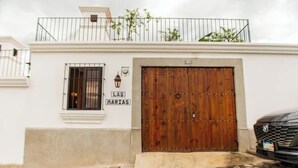 Un edificio con una puerta de madera grande, una ventana pequeña con una reja de metal y un letrero sobre la puerta que dice 