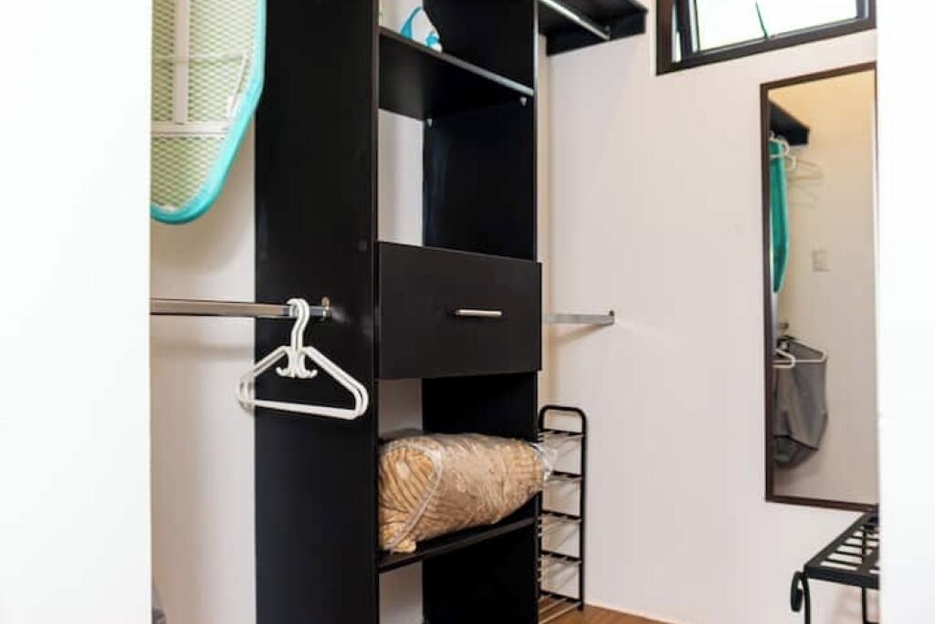 Une petite pièce comprenant un lit superposé, une petite étagère et un miroir.
