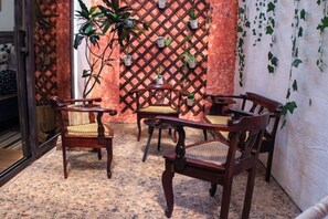 A cozy seating area with wooden chairs and a table, surrounded by potted plants and a lattice wall. - *Beautiful Colonial House* next to Antigua Guatema (Antigua)