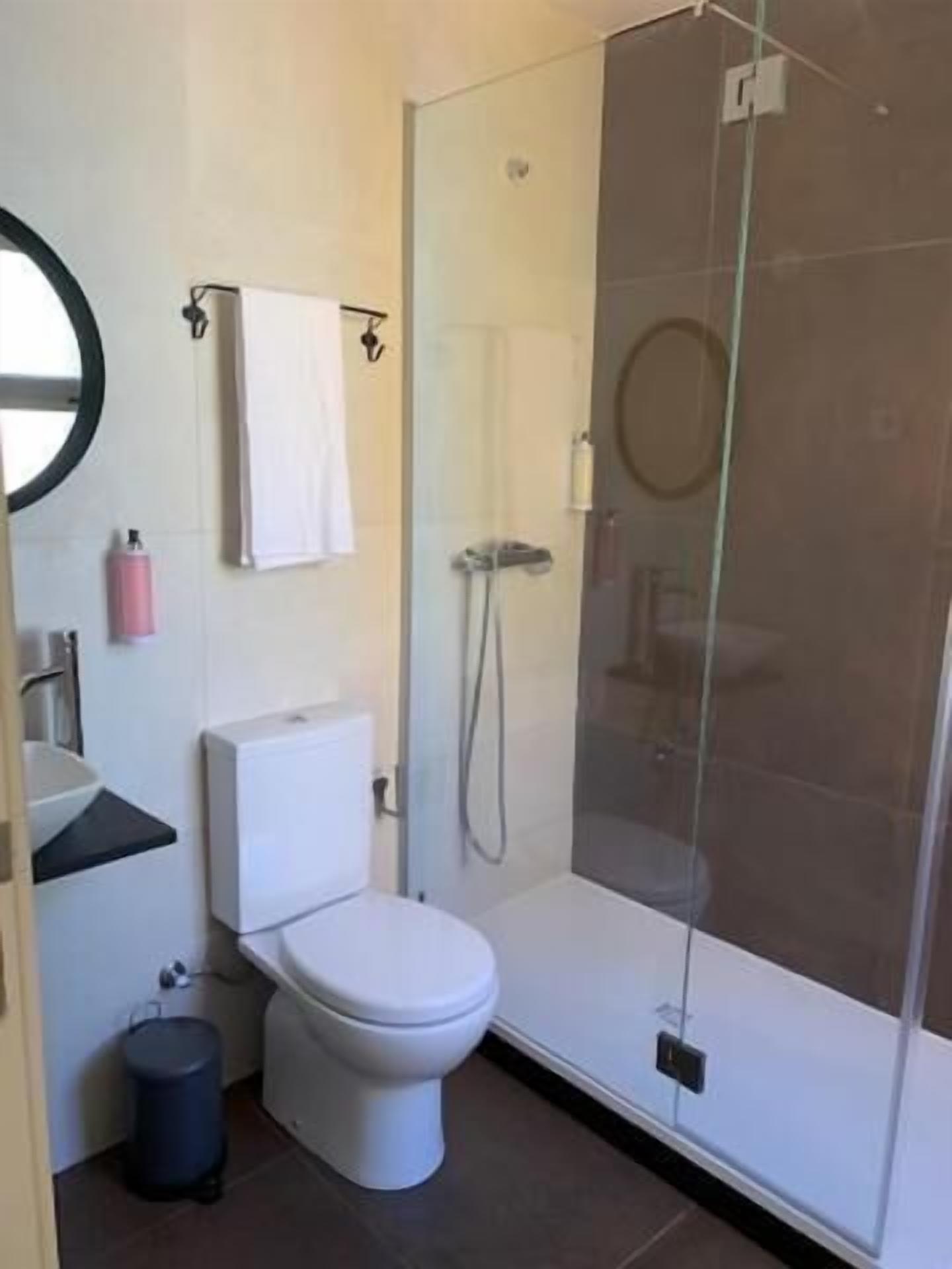 A modern bathroom with a toilet, sink, and glass-enclosed shower.
