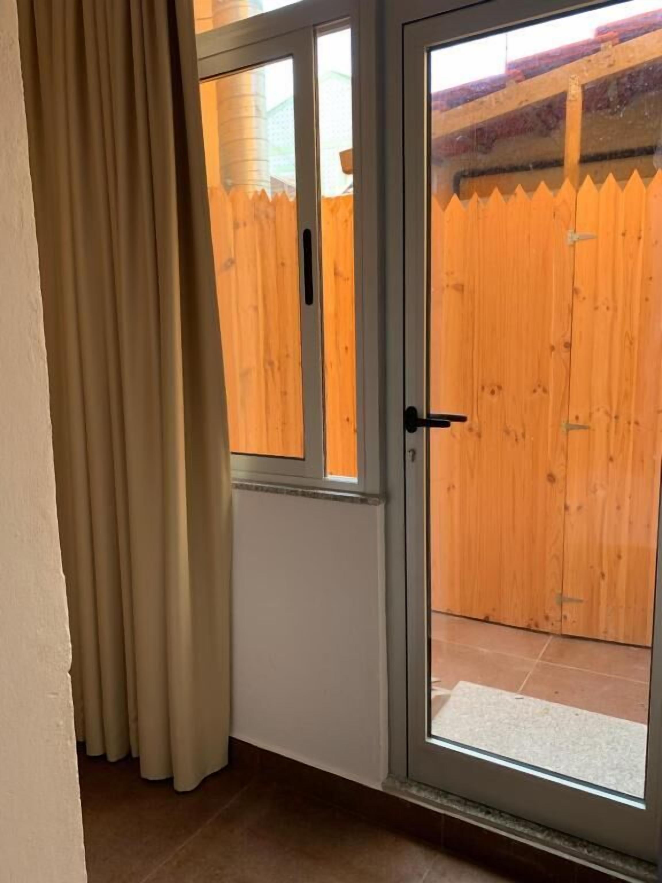 A sliding glass door leading to a wooden deck with a fence.