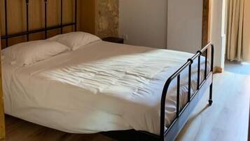 A single bed with a metal frame in a room with a stone wall and wooden paneling.
