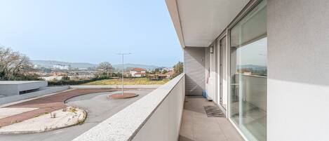 A modern building with a balcony overlooking a parking area and distant landscape.
