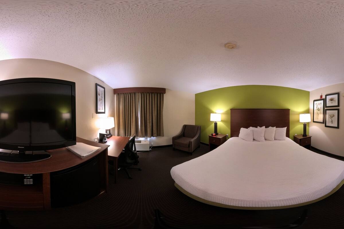 A hotel room with a large bed, a television, a desk, and a chair.