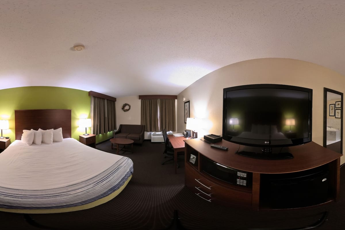 A hotel room with a bed, a TV, a desk, and a chair.