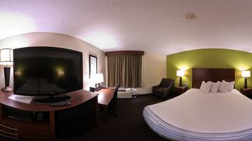 A hotel room with a bed, TV, desk, chair, and lamps.