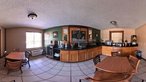 A kitchen with a central island, a dining area with chairs, and a large window. - Coratel Plus Suites by Jasper Black River Falls (Black River Falls)