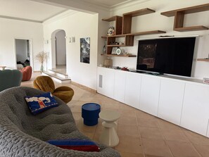 Ein modernes Wohnzimmer mit einem großen grauen Sofa, einem kleinen runden Tisch und einem flachbildfernseher, der an einem weißen Schrank befestigt ist.
