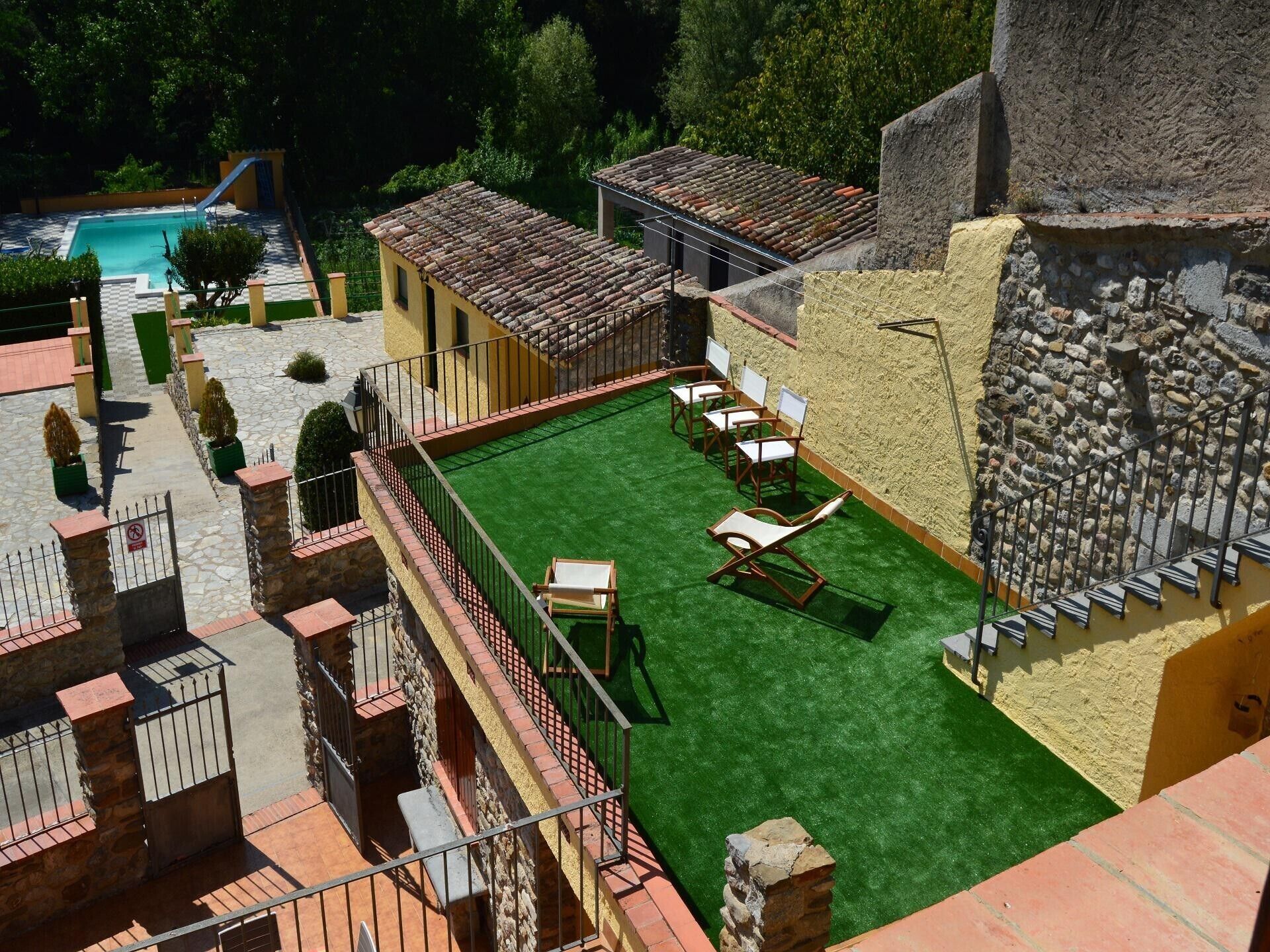 A courtyard with a pool, outdoor seating, and a stone wall.