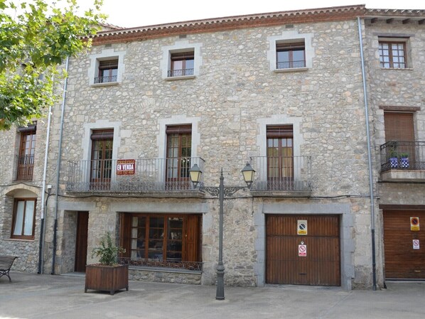 Un bâtiment en pierre doté de nombreuses fenêtres, de balcons et d’une enseigne indiquant une vente.