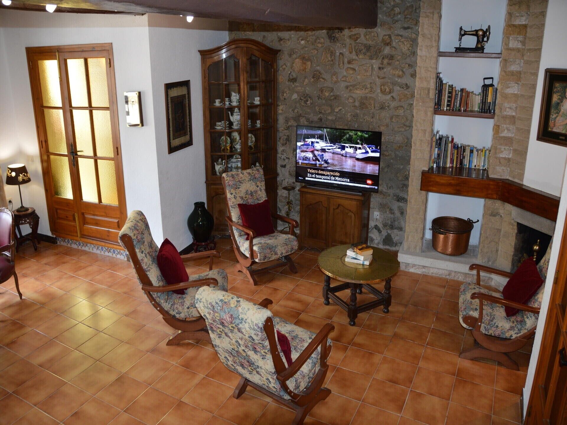 A living room with a television, wooden furniture, a stone wall, and a fireplace.