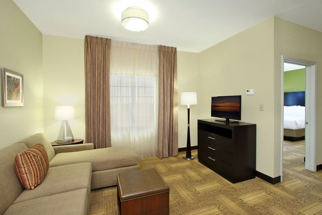 A hotel room with a sofa, a TV, a desk, and a lamp.