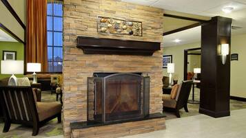A lobby with a stone fireplace, seating area, and a view of the outdoors.