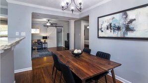 A dining area with a wooden table, black chairs, and a bowl of bread. - Charming 3BR Retreat in Plaza Close to Uptown (Charlotte)