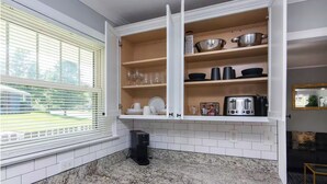 A kitchen with white cabinets, a coffee maker, and a window with blinds. - Charming 3BR Retreat in Plaza Close to Uptown (Charlotte)