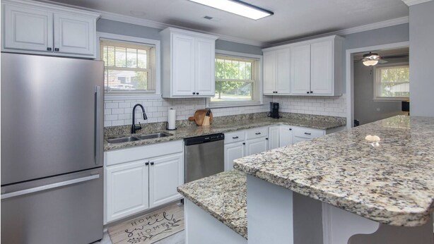 A modern kitchen with white cabinets, granite countertops, stainless steel appliances, and a large island. - Charming 3BR Retreat in Plaza Close to Uptown (Charlotte)