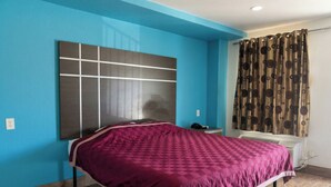 A bedroom with a large bed, a headboard, a bedside table, a telephone, and a window with curtains. - Golden Motel Near Houston Medical Center (Houston)