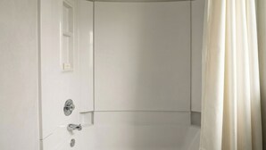 A white bathroom with a shower, a door, and a curtain. - Golden Motel Near Houston Medical Center (Houston)
