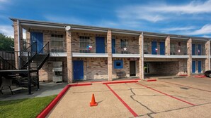 A multi-story hotel with brick exterior, balconies, and a parking area with marked spaces. - Golden Motel Near Houston Medical Center (Houston)