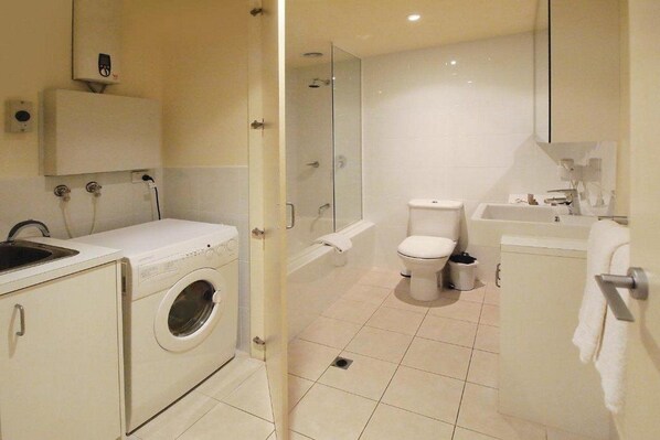 Een moderne badkamer met een wasmachine, toilet, bad en wastafel.