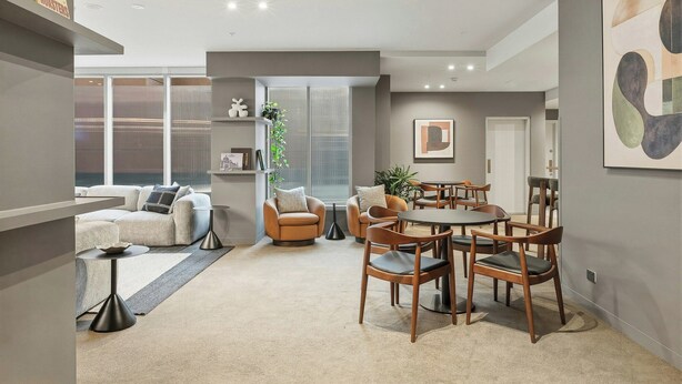 Uma sala de estar moderna com sofá, poltronas, mesa de jantar com cadeiras, mesa de centro e estante de livros.