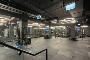 Ett modernt gym med en mängd olika träningsredskap, digitala skärmar och en ren och väl upplyst interiör.