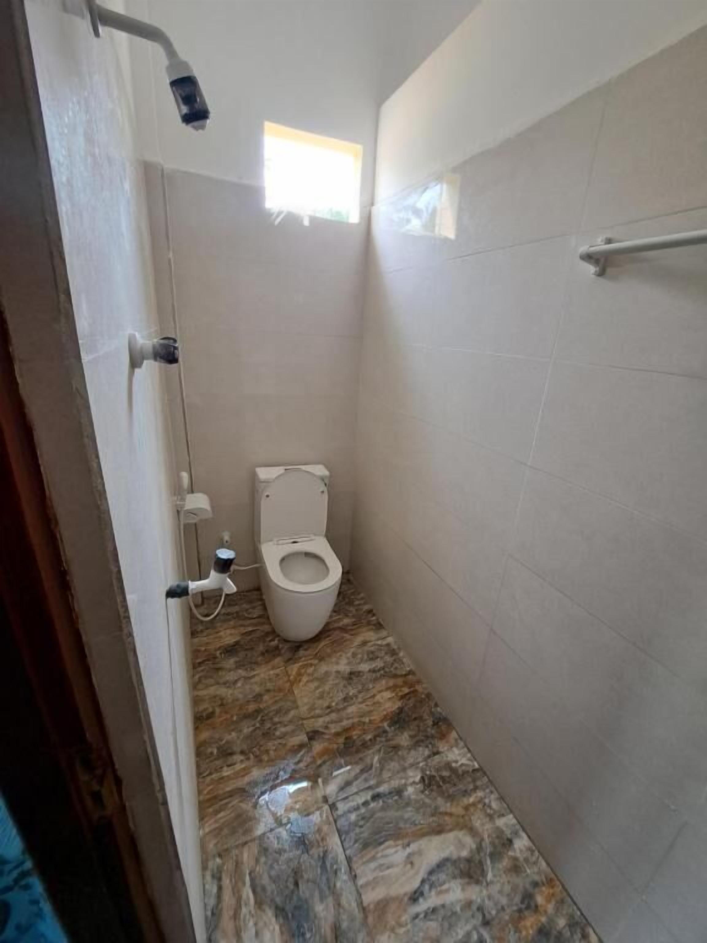 Un baño pequeño con inodoro, ducha y suelo de mármol.