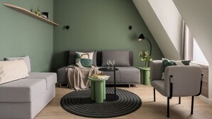 Un soggiorno moderno con un divano grigio, una poltrona verde, un tavolino rotondo e una lampada da terra nera.