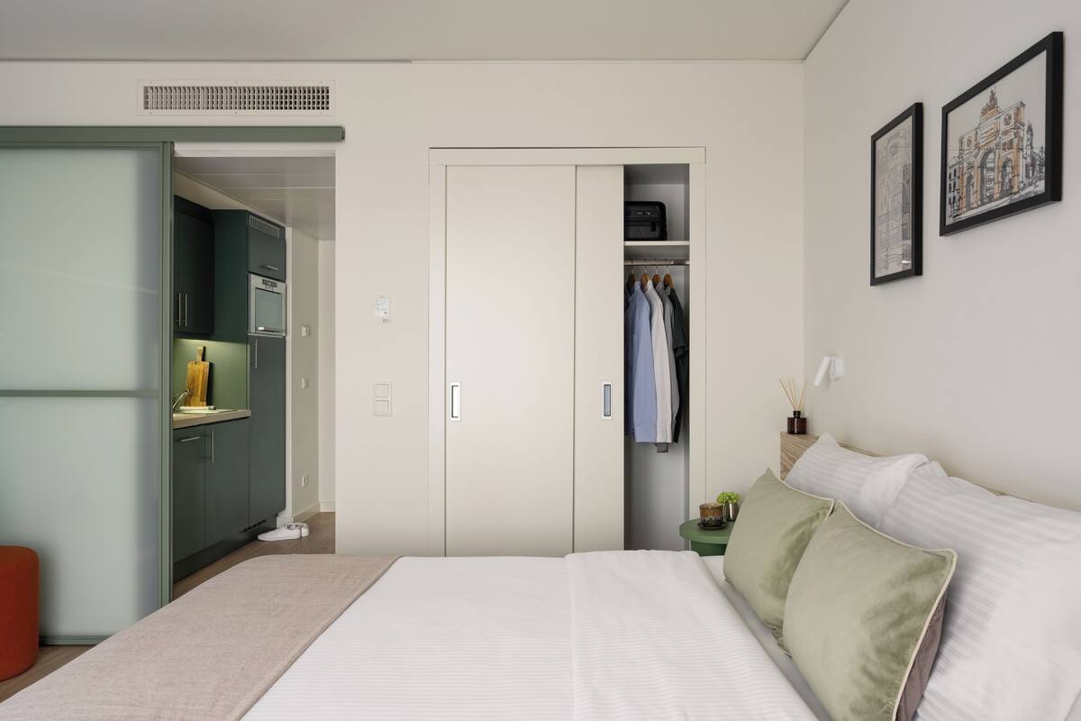 Une chambre à coucher comprenant un lit, une armoire, une petite table et un tableau accroché au mur.