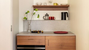 A kitchen with a wooden cabinet, a coffee maker, a red plate, and a vase with green leaves. - Bob W Stockholm Sodermalm (Stockholm)