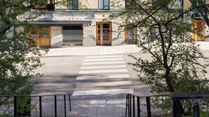 A multi-story building with a central entrance, large windows, and a crosswalk leading to the entrance. - Bob W Stockholm Sodermalm (Stockholm)