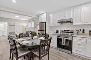 A modern kitchen with white cabinets, stainless steel appliances, and a dining area with a round table and chairs.