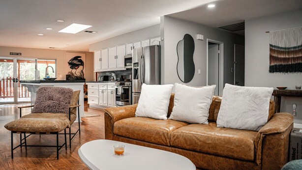 A modern living room with a leather sofa, a white coffee table, and a wooden floor. - River, Pool, and Jacuzzi in 4 Bedroom House (Three Rivers)