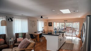 A spacious living area with a kitchen, dining area, and a view of the outdoors. - River, Pool, and Jacuzzi in 4 Bedroom House (Three Rivers)