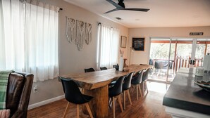 A dining area with a wooden table, black chairs, and a ceiling fan. - River, Pool, and Jacuzzi in 4 Bedroom House (Three Rivers)