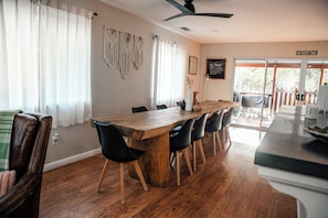 A dining area with a wooden table, black chairs, and a ceiling fan. - River, Pool, and Jacuzzi in 4 Bedroom House (Three Rivers)