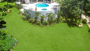 A large, modern house with a swimming pool, surrounded by lush greenery and palm trees. - Tranquil 4BR Villa Pool Spa Resort Access (Montego Bay)