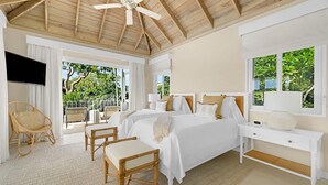 A bedroom with a large bed, a desk, a chair, and a ceiling fan. There is a window with a view of greenery outside. - Tranquil 4BR Villa Pool Spa Resort Access (Montego Bay)