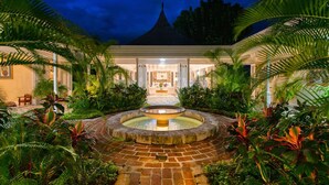 A courtyard with a central fountain, surrounded by lush greenery and a building with a tiled roof. - Private 2BR Open-air Villa Panoramic Views Pool (Montego Bay)