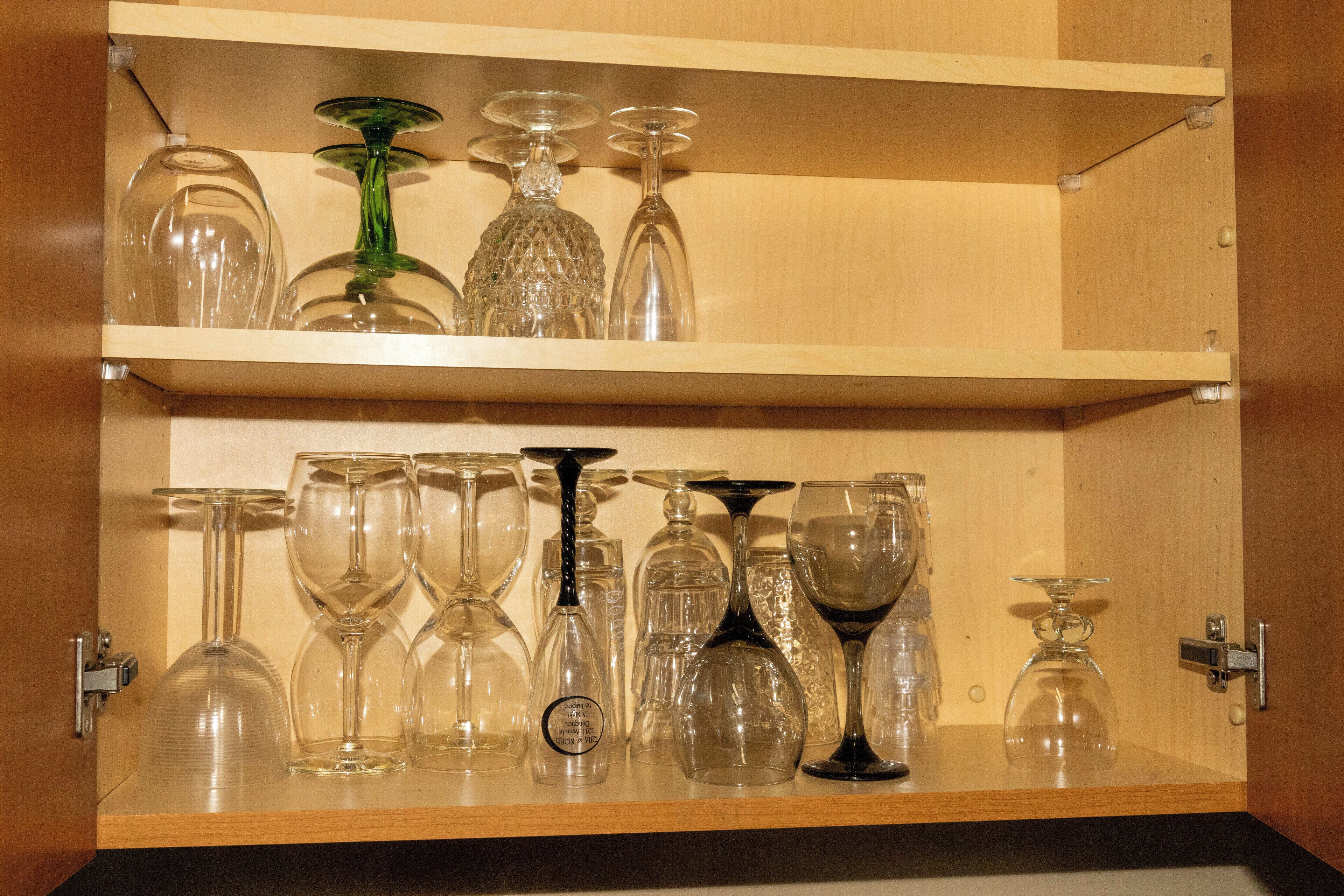 Un armario de madera con dos estantes que exhiben varios copas de vino.