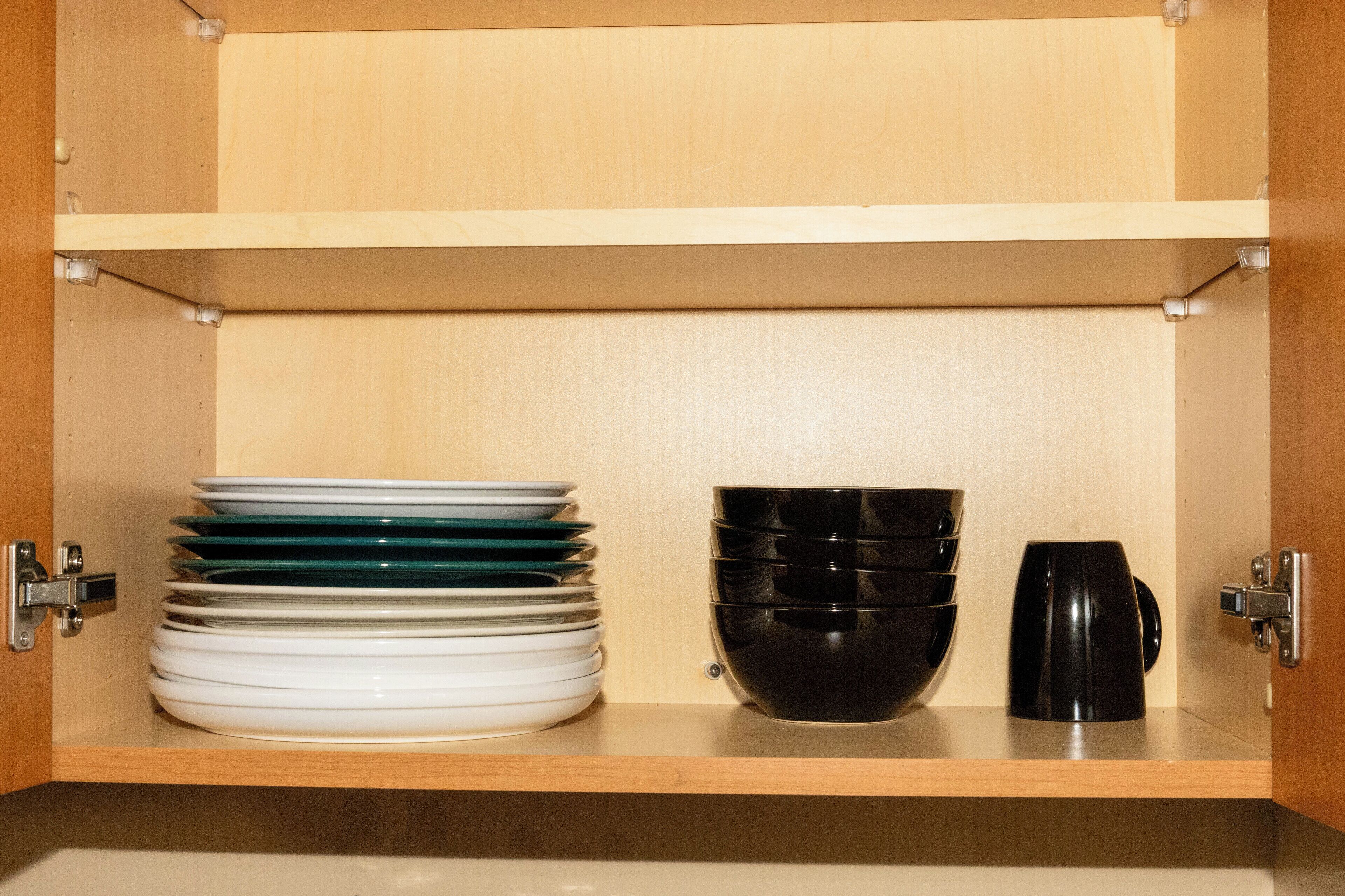 A wooden cabinet with shelves holding stacked plates and bowls.
