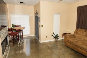 A spacious living room with a fireplace, a dining area with a table and chairs, and a brown sofa. - Fair and Walker (Atlanta)