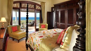 A spacious bedroom with a large bed, a balcony with a view of the ocean, and a ceiling fan. - Expansive 6BR Estate Panoramic Sea Views Pool Resort Access (Montego Bay)