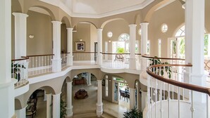 A spacious interior with multiple levels, white columns, and a central open area with furniture. - Sprawling 7BR Villa Overlooking the Sea Pool Hot Tub Resort Access (Montego Bay)