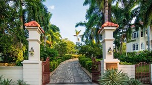 A gated entrance with a stone pathway leading to a building, surrounded by lush greenery and palm trees. - Sprawling 7BR Villa Overlooking the Sea Pool Hot Tub Resort Access (Montego Bay)