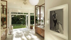 A spacious bathroom with a large mirror, a vanity, and a shower area. - Nature-inspired 4BR Modern Villa Pool Resort Access (Montego Bay)