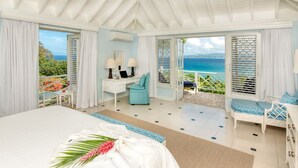 A bedroom with a large bed, a desk with two lamps, and a view of the ocean through open windows. - Private 4BR Open-air Villa Panoramic Views Pool (Montego Bay)